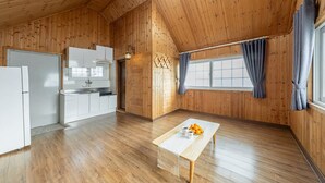 A wooden interior with a kitchen, dining table, and a window with curtains. - Ganghwado Gagopa Family Group Pension (Incheon)