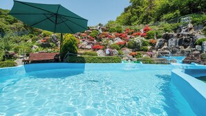 A clear blue pool with a wooden bench and a green umbrella. - Ganghwado Gagopa Family Group Pension (Incheon)