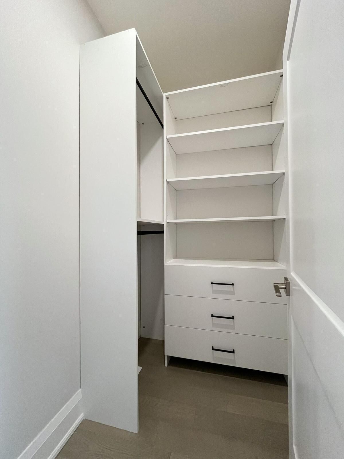 A walk-in closet with open doors, multiple shelves, and drawers.