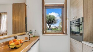 A compact kitchen with a window, a toaster, and a bowl of fruit on the counter. - House Tiziana Close by Mare Argentario, Manciano, Italy (Manciano)