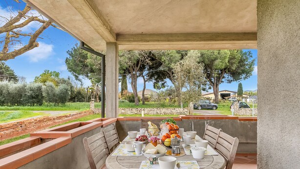 An outdoor dining area with a table set for four, surrounded by a concrete wall and wooden benches. - House Tiziana Close by Mare Argentario, Manciano, Italy (Manciano)