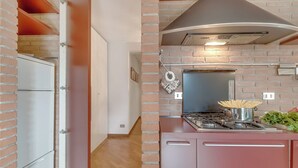 Una cocina con pared de ladrillo, estufa y un colgador para ollas.