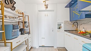 Eine moderne Küche mit weißen Schränken, einem blauen Gerät und einer Wanddekoration.