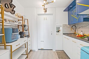 Eine moderne Küche mit weißen Schränken, einem blauen Gerät und einer Wanddekoration.