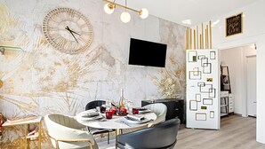 Ein moderner Essbereich mit einem runden Tisch, Stühlen und einem an der Wand befestigten Fernseher.