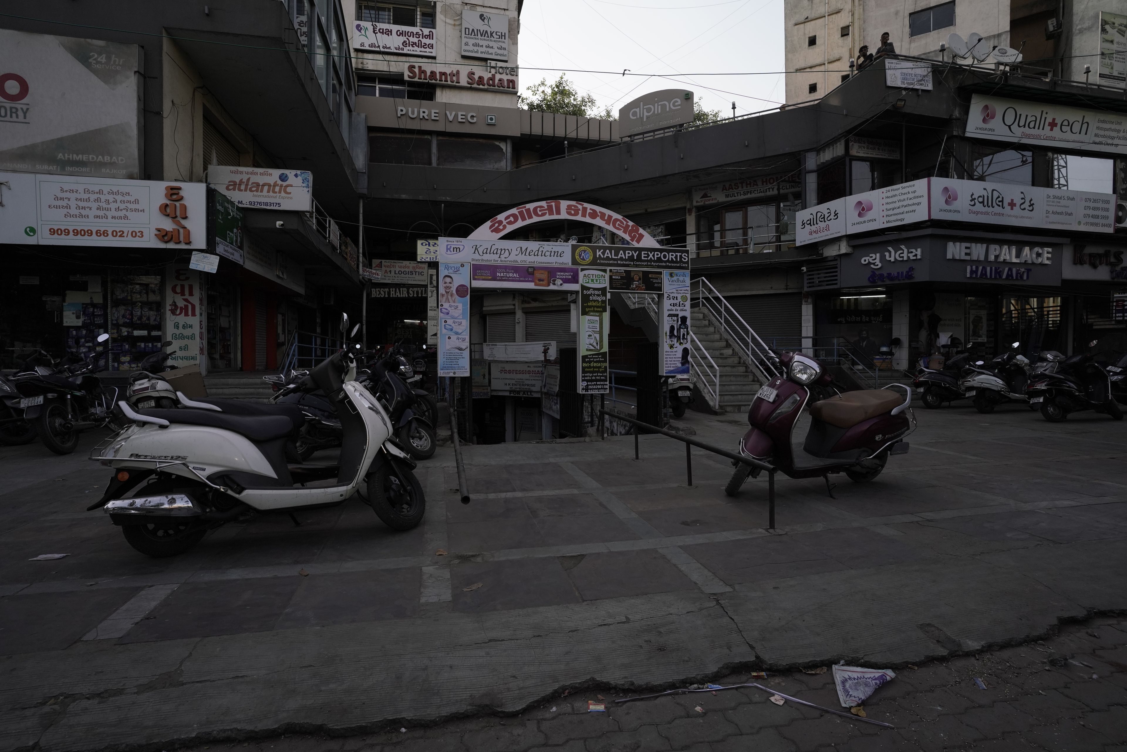 A street view with a building that has a sign for 'Shanti Sadan' and 'Pure Veg' restaurant. There are parked scooters in front of the building.