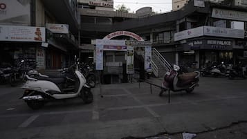 A street view with a building that has a sign for 'Shanti Sadan' and 'Pure Veg' restaurant. There are parked scooters in front of the building.
