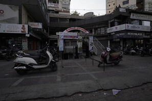 A street view with a building that has a sign for 'Shanti Sadan' and 'Pure Veg' restaurant. There are parked scooters in front of the building. - Hotel Shanti Sadan (Ahmedabad)