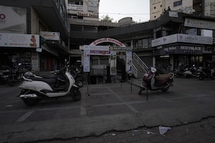 A street view with a building that has a sign for 'Shanti Sadan' and 'Pure Veg' restaurant. There are parked scooters in front of the building.