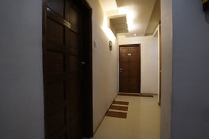 A hallway with two wooden doors, a light fixture on the ceiling, and a tiled floor.