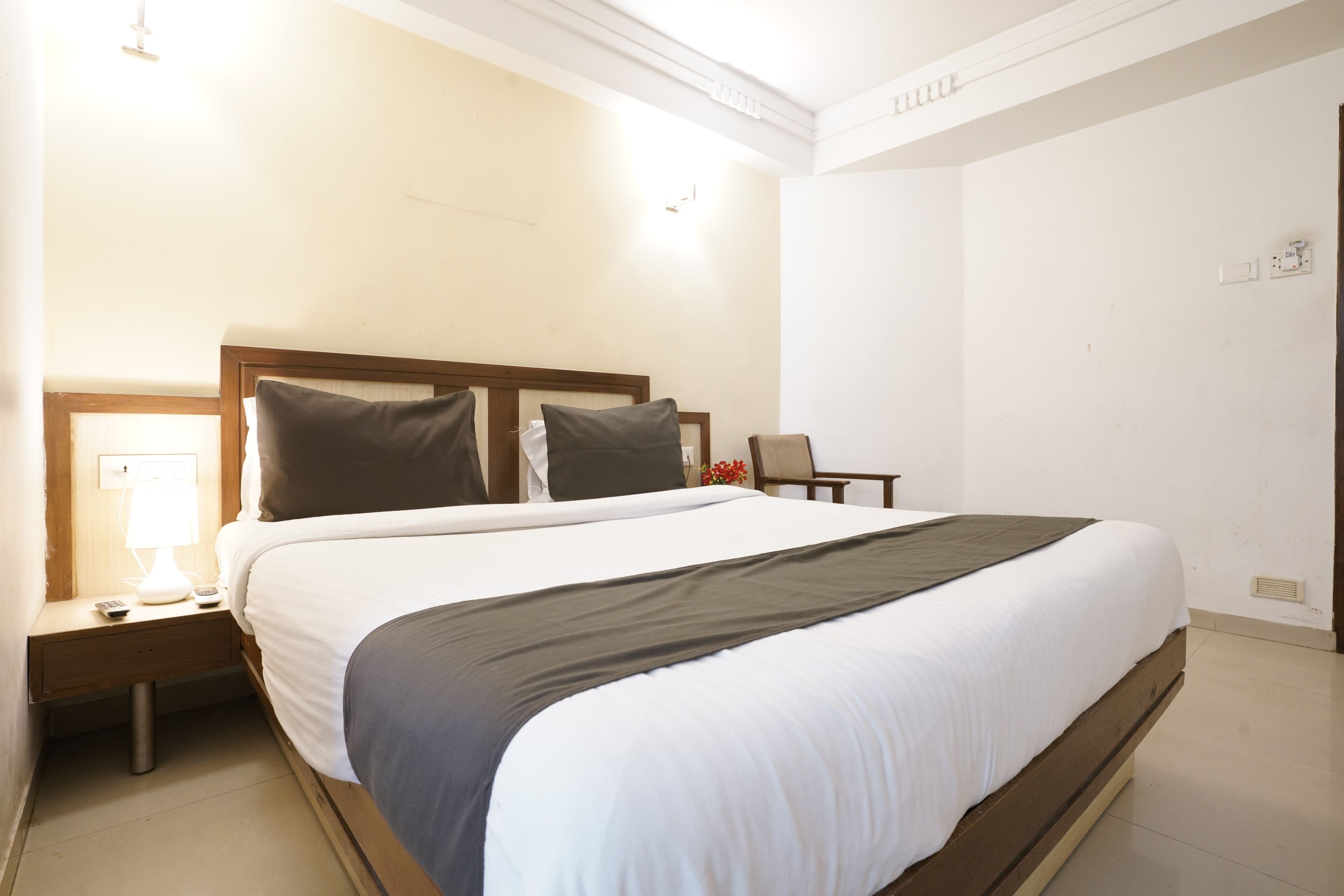 A hotel room with a large bed, a bedside table with a lamp, and a chair.