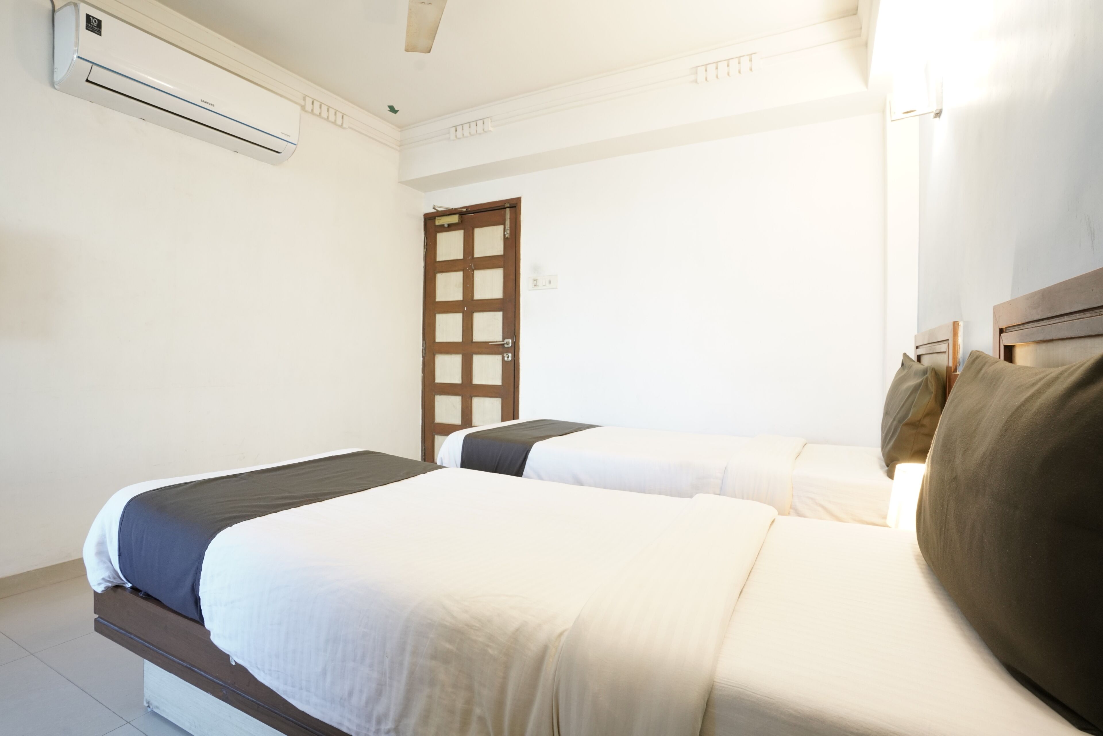 Une chambre d’hôtel avec deux lits, une porte et un appareil de climatisation.