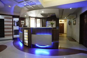 A reception area with a digital clock, reception desk, and a decorative vase.