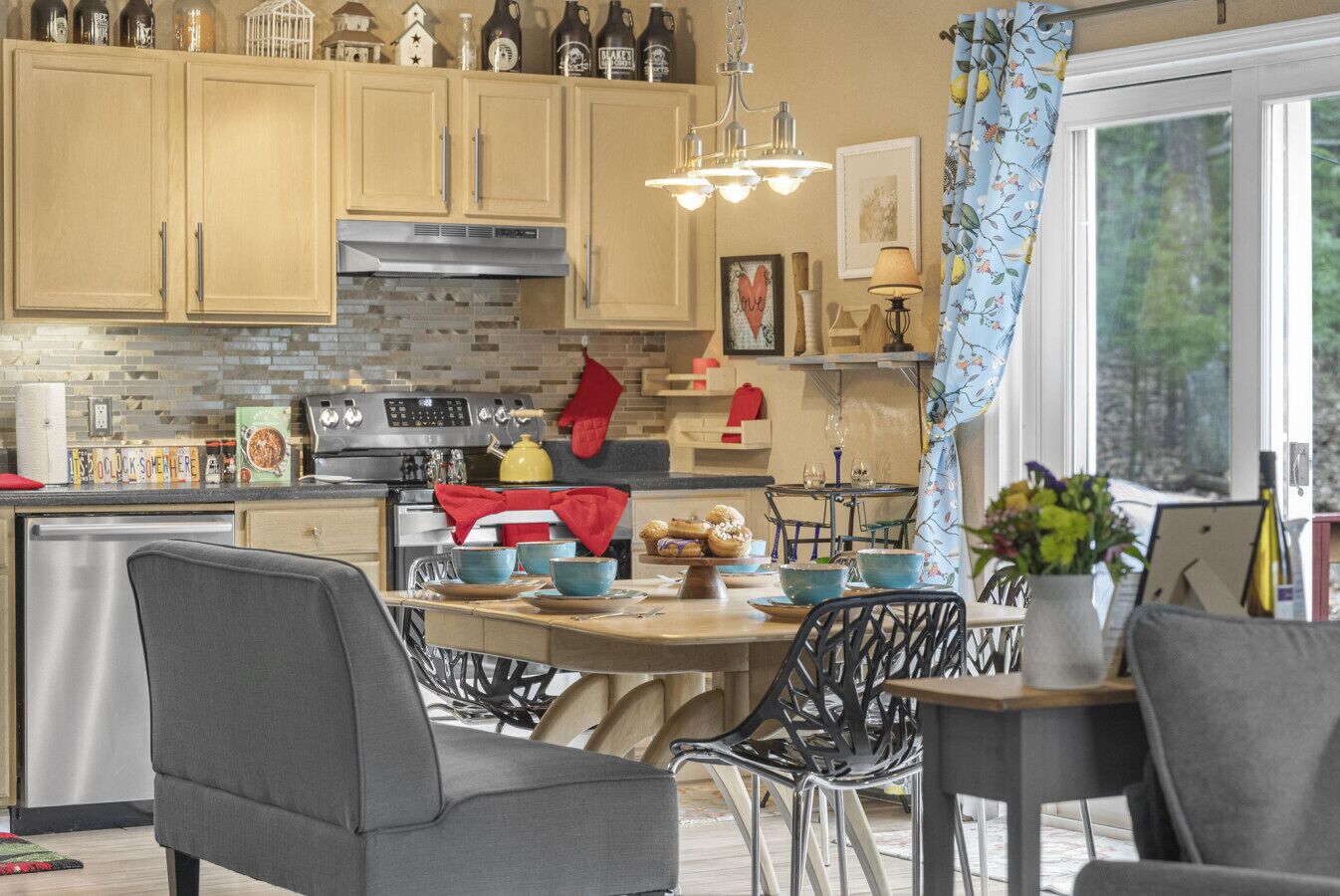 A kitchen with wooden cabinets, a stainless steel stove, and a dining area with chairs and a table.