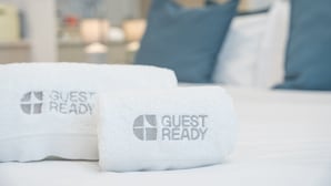 Due asciugamani bianchi con la scritta 'GUEST READY' su un letto.