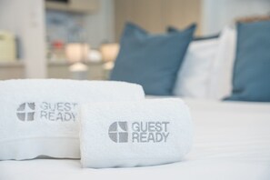 Zwei weiße Handtücher mit dem Aufdruck 'GUEST READY' auf einem Bett.