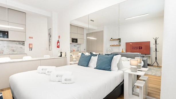 Una camera d'albergo moderna con un letto grande, comodini, una televisione e un angolo cottura.