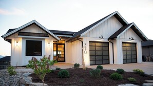 A modern two-story house with a garage, a covered entryway, and a landscaped front yard with a stone border. - Poolside retreat with private basketball court (Vernon)