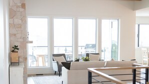 A modern living room with a stone accent wall, a wooden ceiling, and large windows. - Poolside retreat with private basketball court (Vernon)
