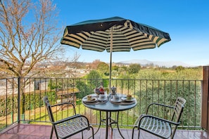 Ein Balkon mit Tisch, Stühlen und Sonnenschirm.