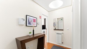 Zona de recepción de hotel con un mostrador de madera, un mapa enmarcado, una planta pequeña en maceta, un espejo, un termostato y un radiador.