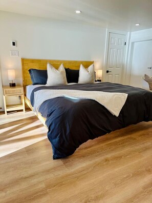A bedroom with a bed, bedside tables, a door, and a light fixture.