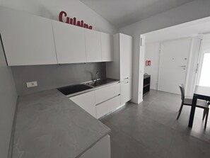 A modern kitchen with white cabinets, a black countertop, and a sink. - Villa LANTERNA - Lignano Sabbiadoro (Lignano Sabbiadoro)