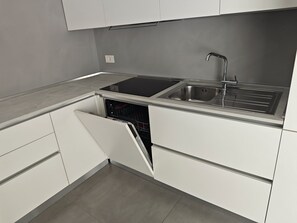 A modern kitchen with a built-in dishwasher, a stainless steel sink, and white cabinetry. - Villa LANTERNA - Lignano Sabbiadoro (Lignano Sabbiadoro)