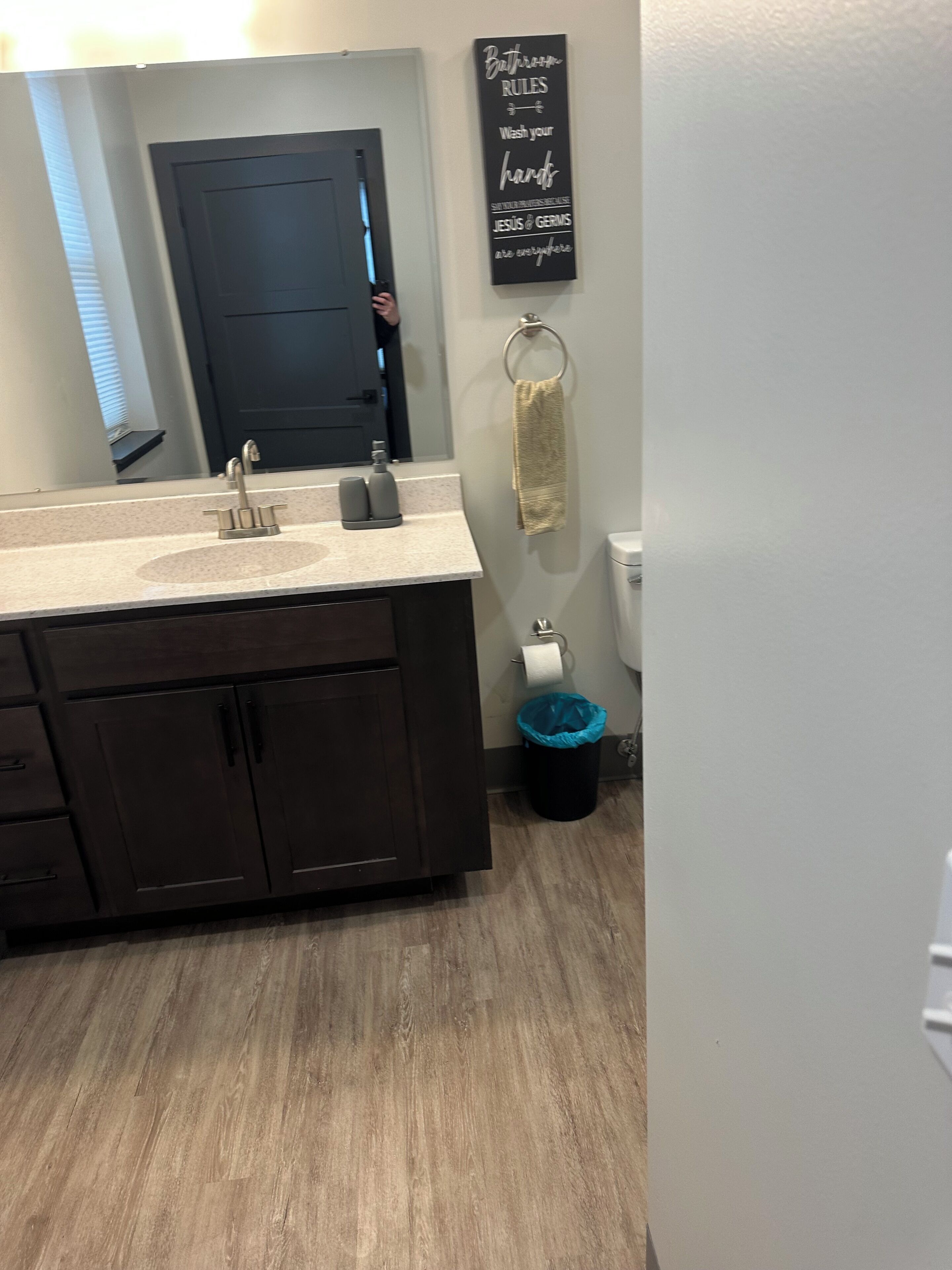 A bathroom with a dark wooden vanity, a sink with a faucet, a towel rack, and a toilet.