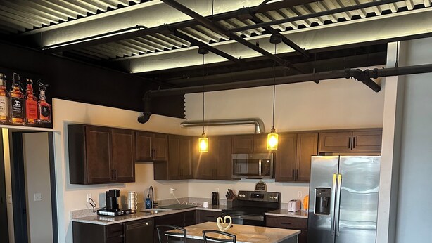 Une cuisine moderne avec des meubles en bois foncé, des appareils électroménagers en acier inoxydable et un îlot central doté de tabourets de bar.