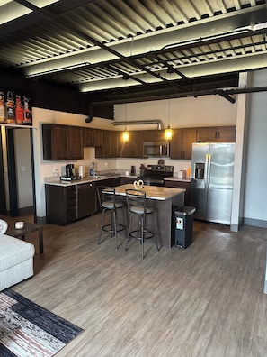 A modern kitchen with dark wooden cabinets, stainless steel appliances, and a central island with bar stools.