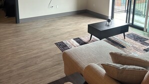 Une chambre moderne dotée d’un grand lit, d’un téléviseur à écran plat fixé au mur, d’une fenêtre donnant sur des immeubles et d’un plafond laissant apparaître les conduits.