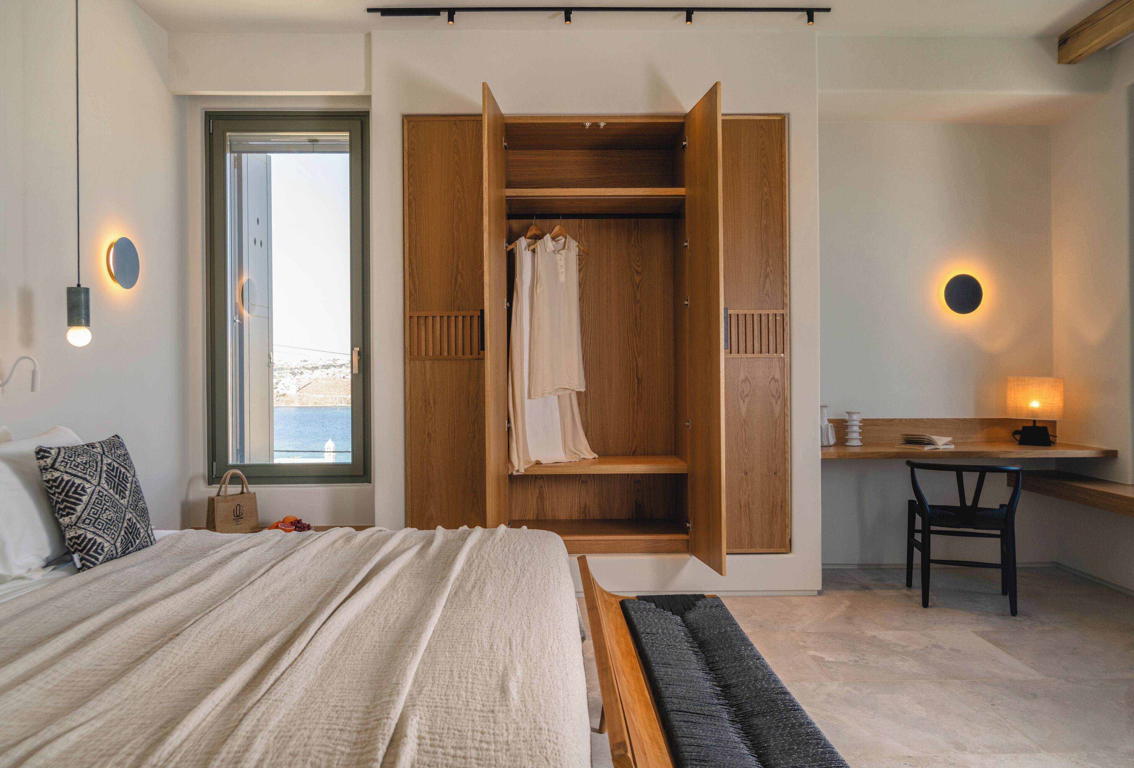 Een slaapkamer met een bed, een houten garderobe, een bureau en een stoel.