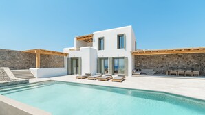 Een modern huis met een zwembad, een terras en een stenen muur.