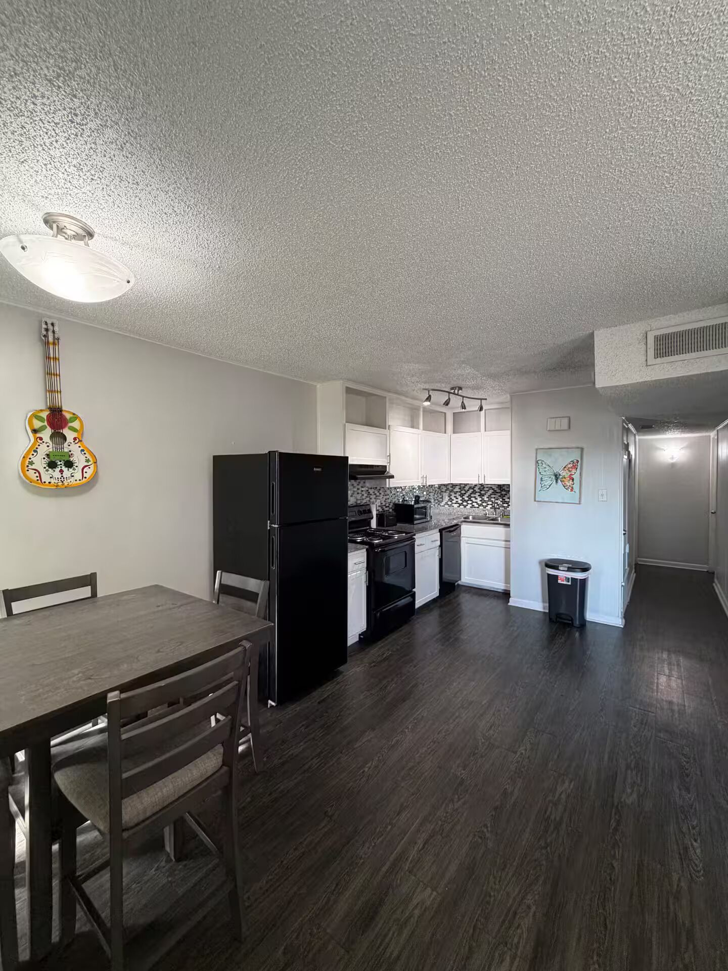 Uma cozinha com mesa de jantar, cadeiras, geladeira, fogão e armários.