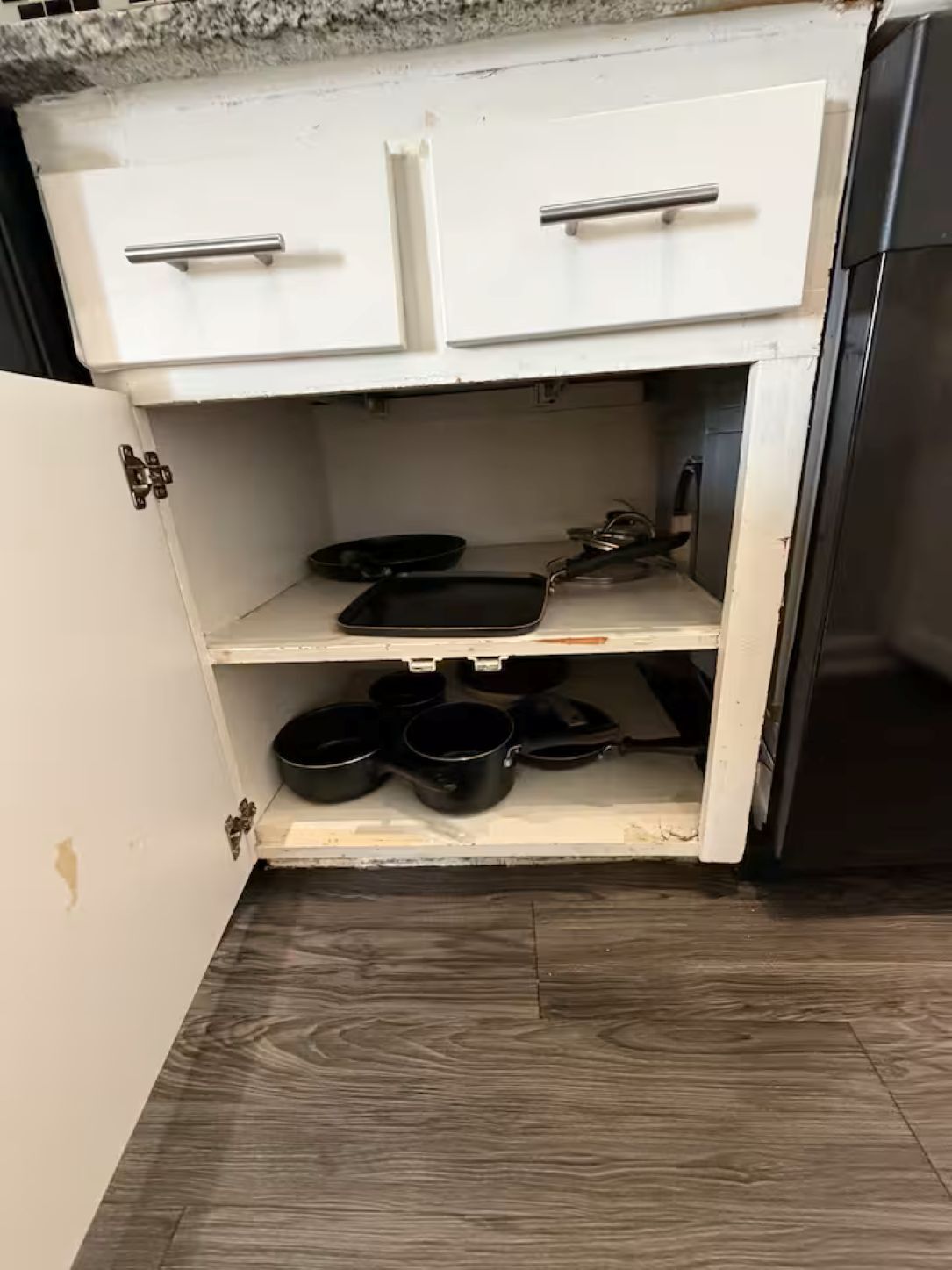 Een keuken met witte kastjes, een aanrecht en een roestvrijstalen koelkast.