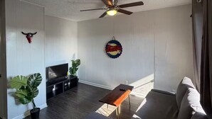 A living room with a sofa, a coffee table, a TV, and a ceiling fan. - Radiant 2x1 apt by West Campus UT! (Austin)