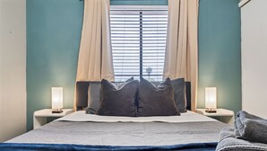 Un lit bien fait, avec des oreillers, une couverture bleue et une serviette pliée posée sur le côté.