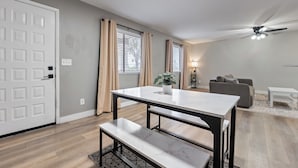 Un salon moderne comprenant une table à manger, un banc, un canapé et un ventilateur de plafond.