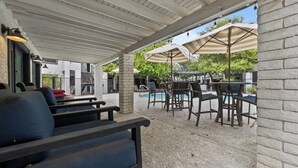 Patio esterno con posti a sedere, ombrelloni e piscina.