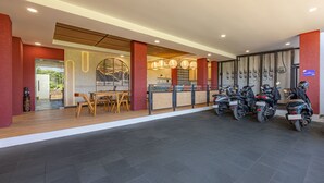 A modern interior with a reception desk, seating area, and motorcycles. - Cove Meraya (Tibubeneng)