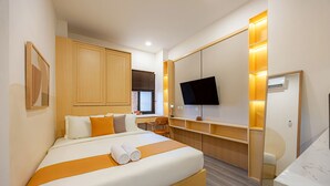 A modern hotel room with a large bed, a desk, a TV, and a mirror. - Cove Meraya (Tibubeneng)