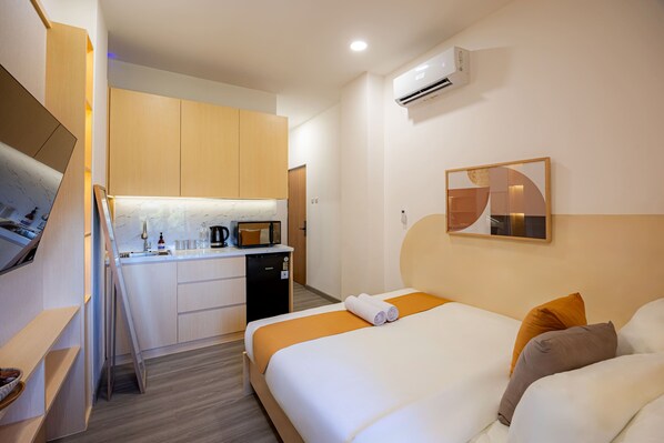 Ein Hotelzimmer mit Bett, Schreibtisch, Mikrowelle und Klimaanlage.