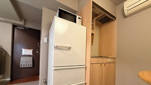 Eine kleine Küche mit einem weißen Kühlschrank, Holzschränken und einer eingebauten Mikrowelle.