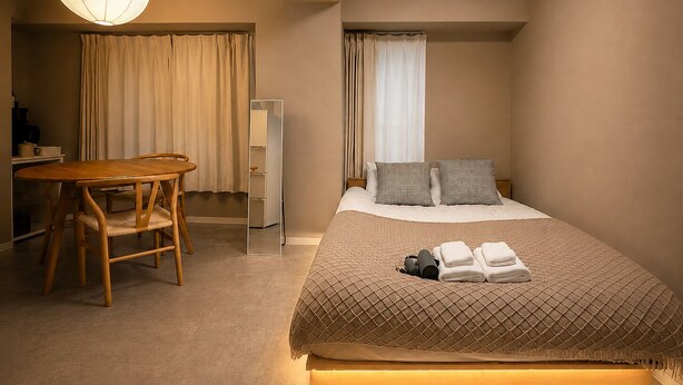 Ein Schlafzimmer mit Bett, Nachttisch, Stuhl und einer Pendelleuchte.