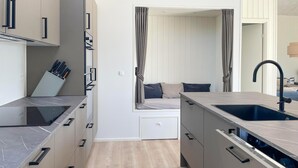 A compact kitchen with a built-in stove, a sink, and a window with curtains.
