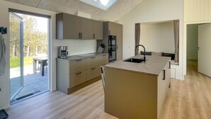 A modern kitchen with a central island, built-in appliances, and a sliding glass door leading to an outdoor area.