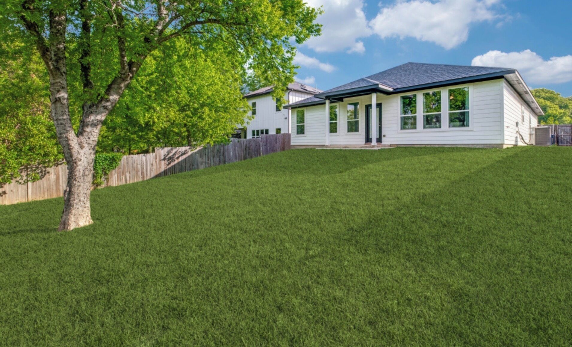 A residential house with a sloped roof, a front porch, and a well-maintained lawn.
