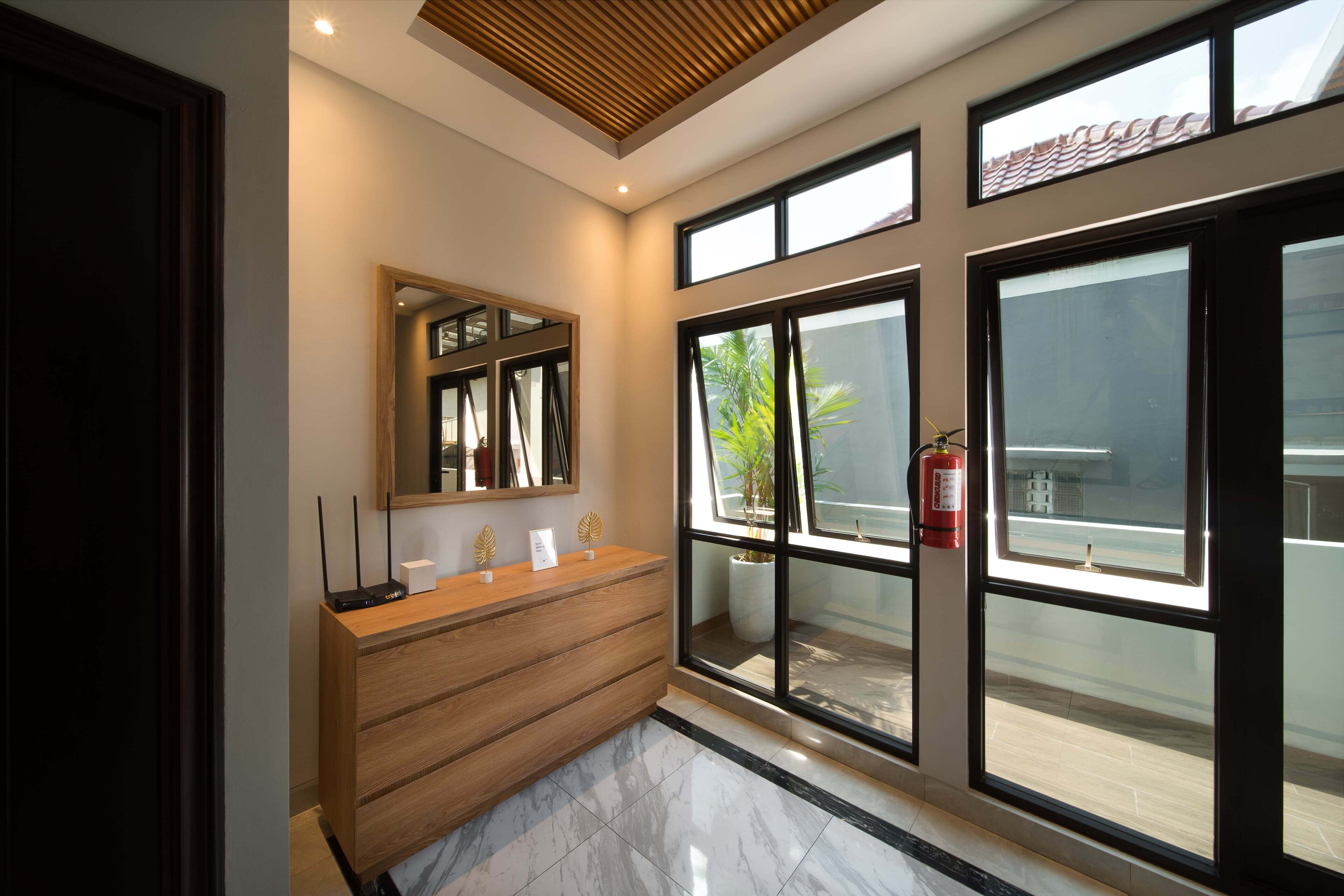 Un bagno moderno con un mobile bagno in legno, ampie finestre e un soffitto con listelli di legno.
