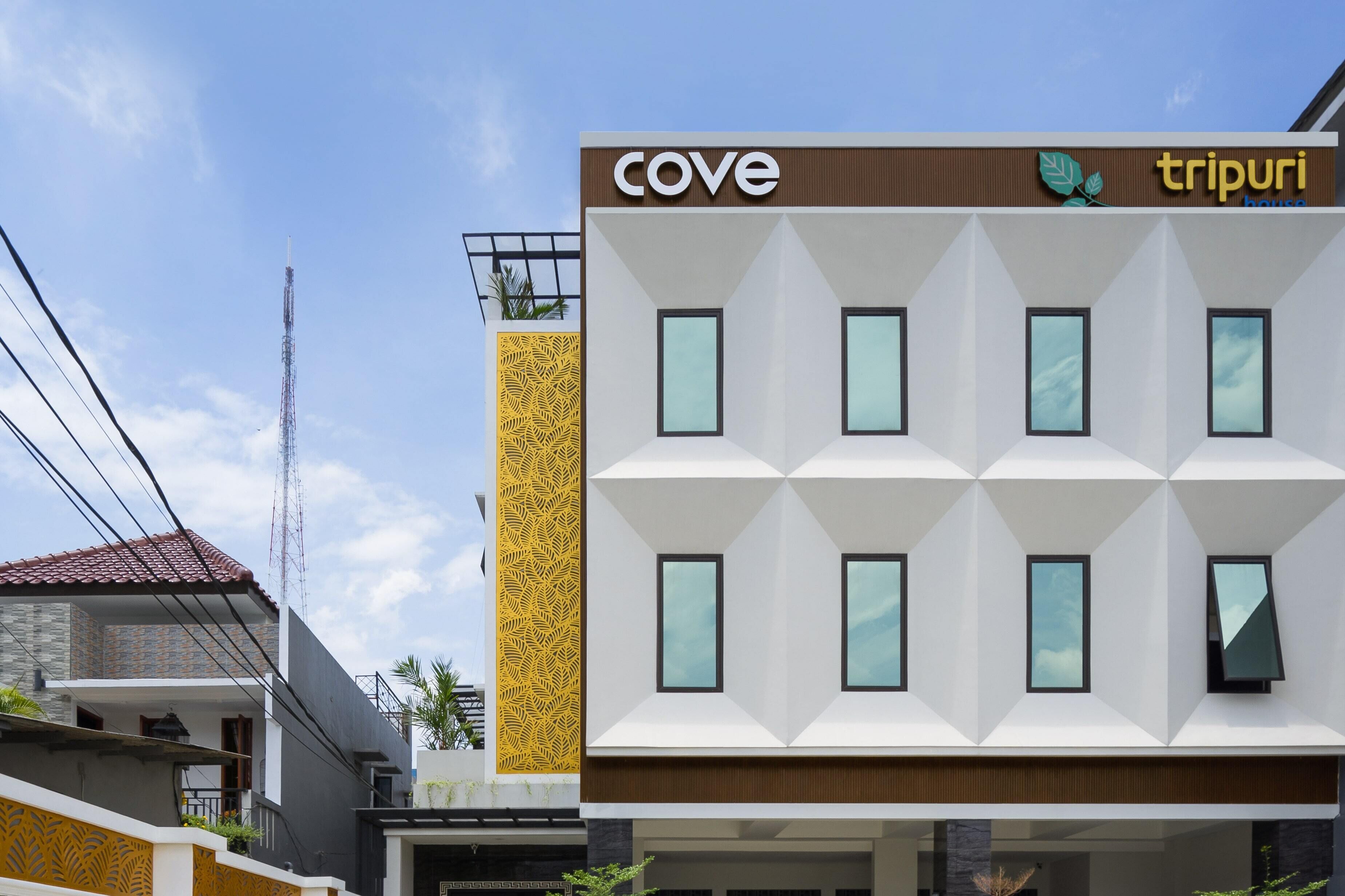 A modern hotel building with a geometric facade, multiple windows, and a visible sign for 'cove' and 'tripuri house'.